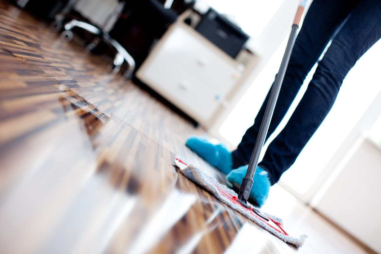Harwood floors being cleaned with a mop and a proper hardwood cleaning solution.