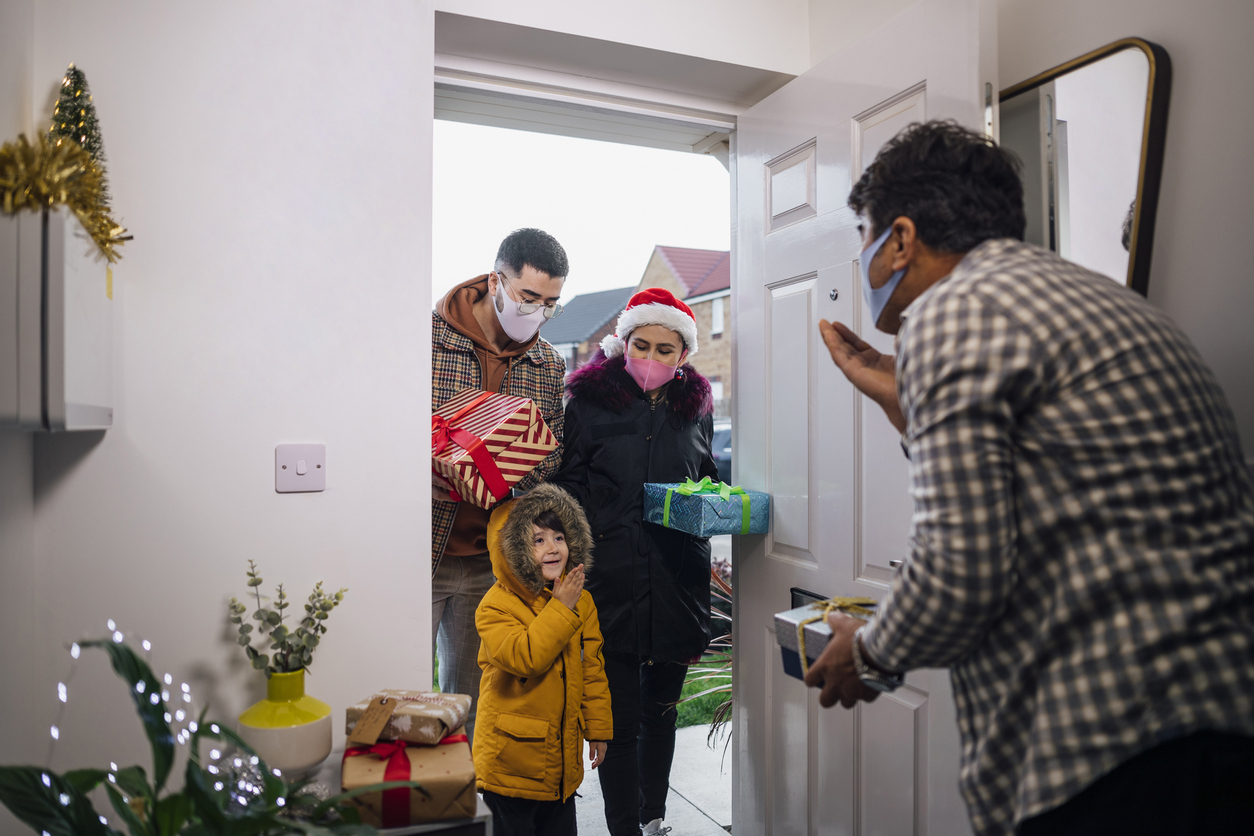 A senior man welcoming his holiday guests into his newly decorated and clean home.