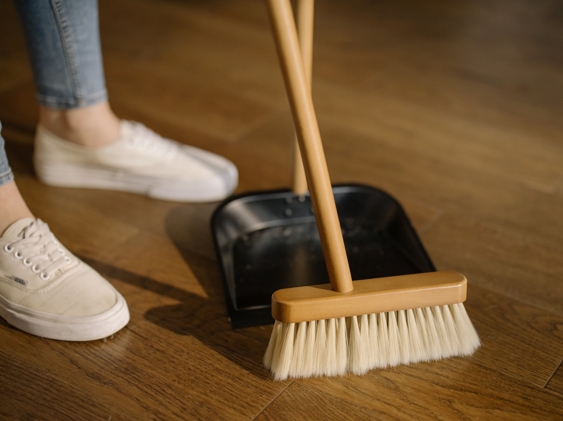 A person cleaning with a broom and a dustpan.