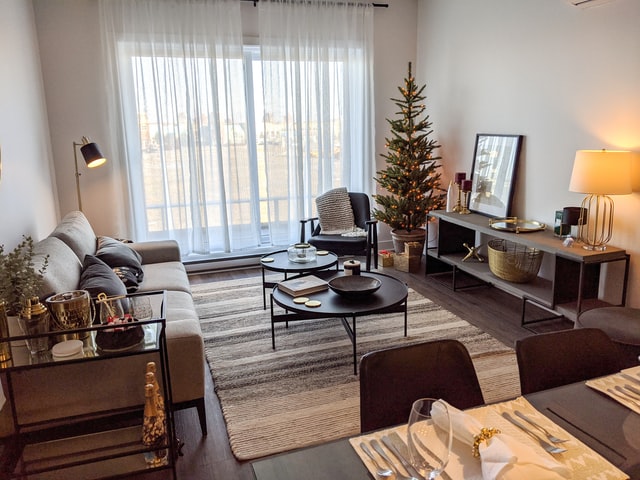 A cozy living room with a large window and a Christmas three next to it