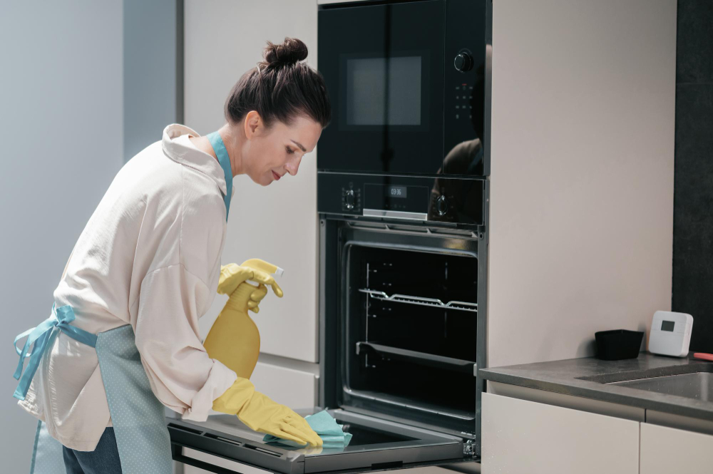 Woman cleaning an oven, avoiding one of the biggest cleaning mistakes