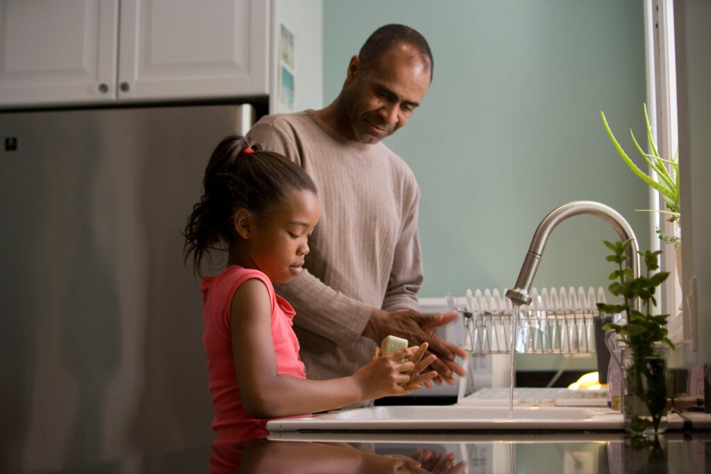 A father helping a daughter do the washing-up.