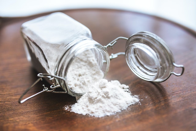A toppled jar of baking soda spilling out, which is a great natural product you can use when sanitizing your fridge.
