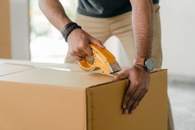 A man taping a box with scotch
