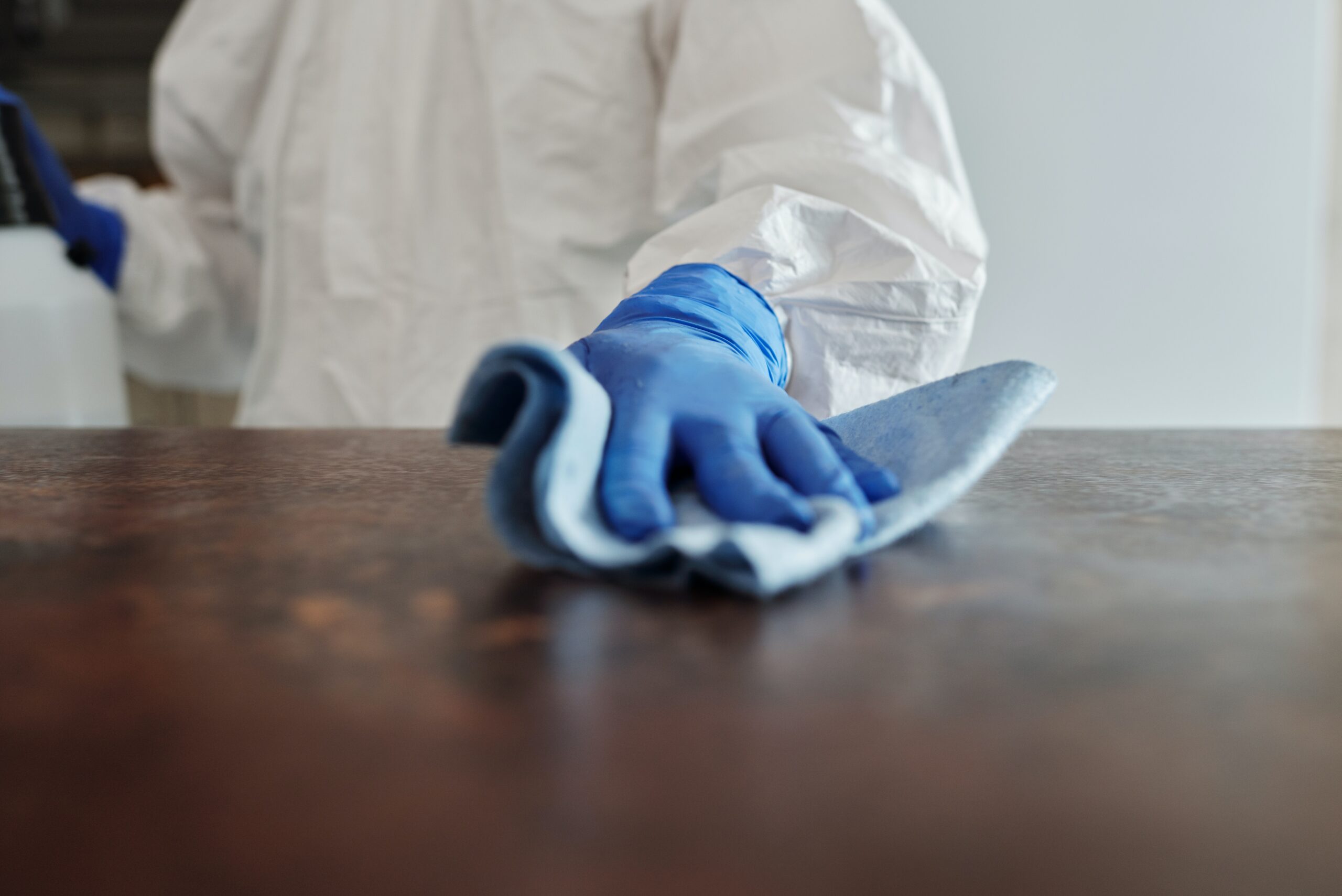 A person wiping a wooden table with a cloth shows one of the ways to clean and maintain secondhand furniture.