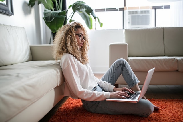 A woman searching how to clean a fabric sofa on a laptop.