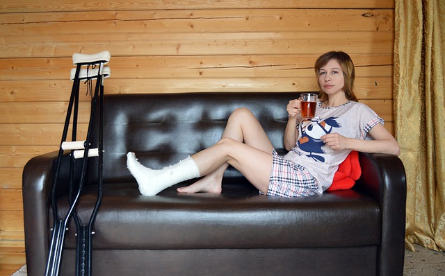 A woman with a broken leg, sitting on a couch with crutches next to her