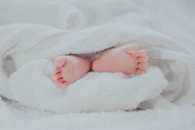 Barefooted baby wrapped in a blanket
