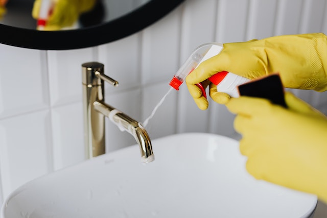 A person with gloves cleaning a bathroom.