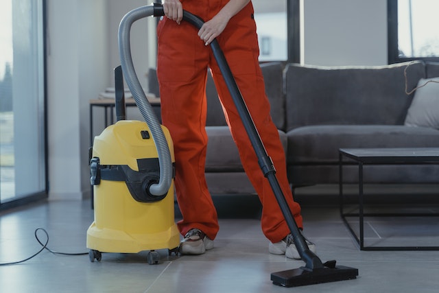 A person cleaning floor with a vacuum cleaner.